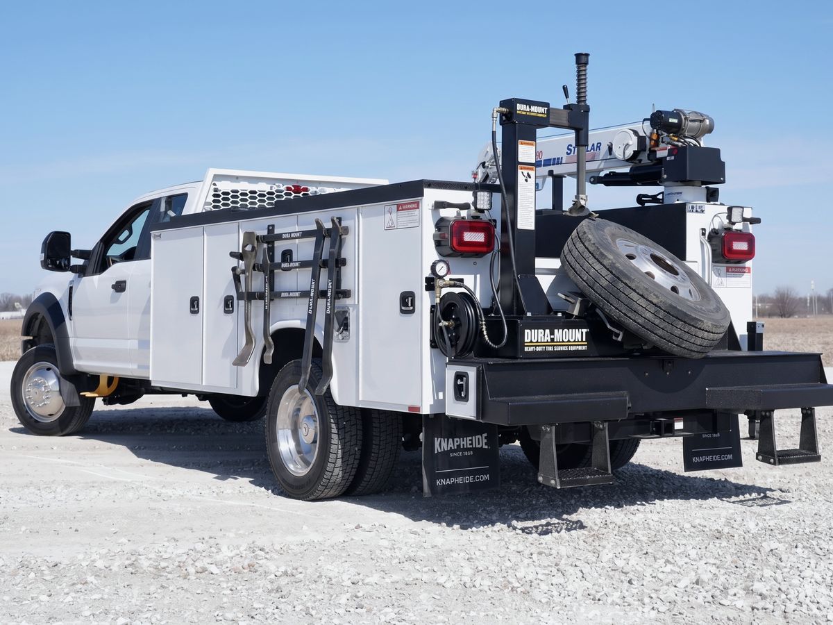 Mobile diesel service truck with tire carrier, crane, and tool compartments