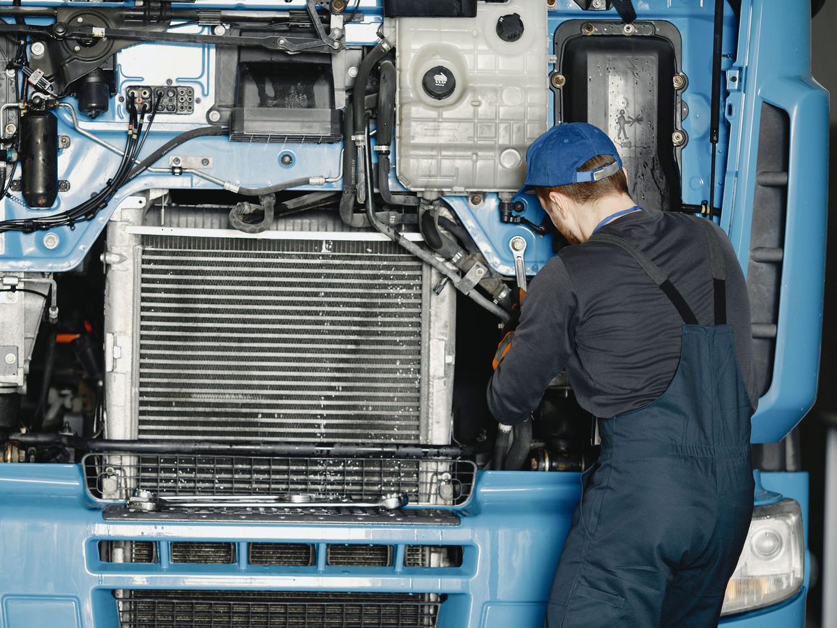 Mechanic working beside the radiator of a truck with the front grille open