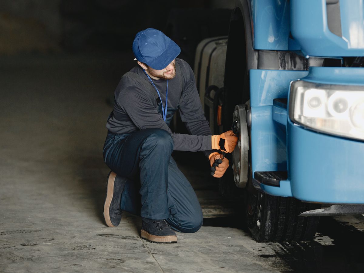 Mechanic loosening lug nuts on a truck wheel with a wrench